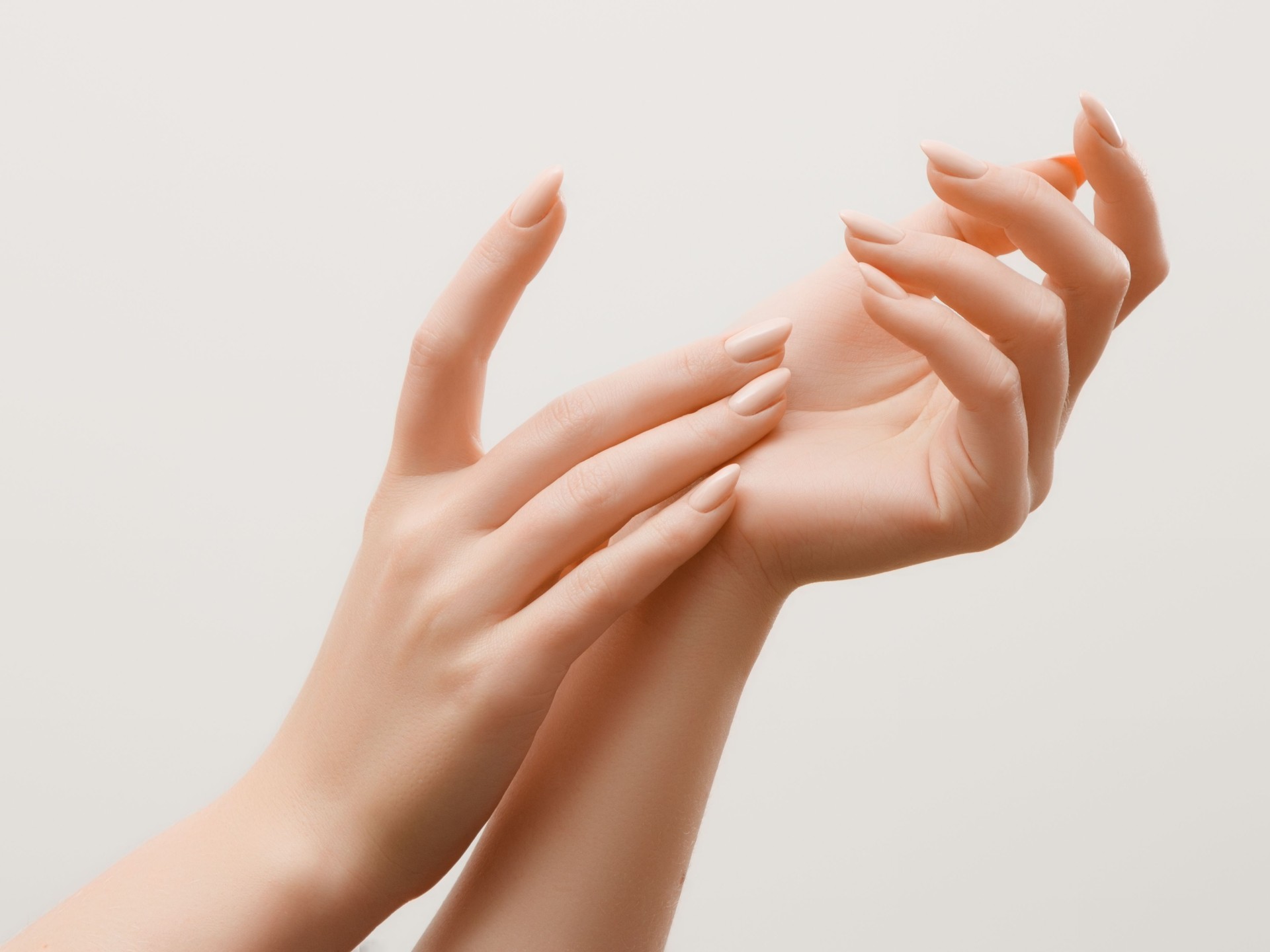 Closeup image of beautiful woman's hands with light pink manicure on the nails. Skin care for hands, manicure and beauty treatment. Elegant and graceful hands with slender graceful fingers